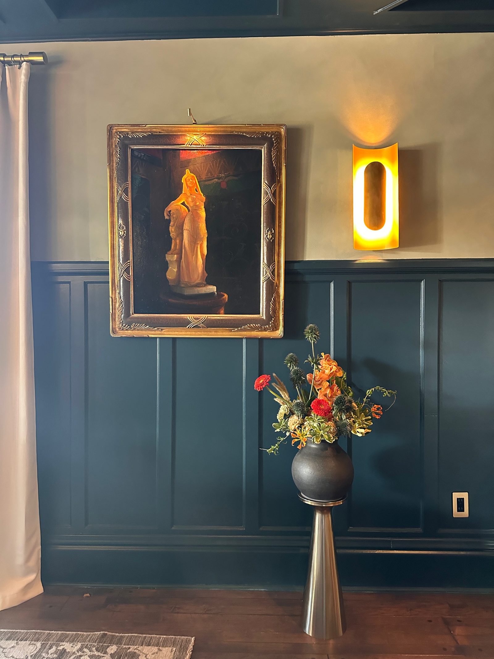 An autumnal arrangement on a pedestal against deep teal panelling